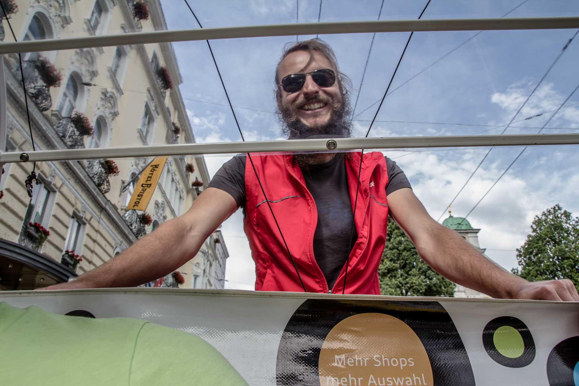 A man in a red shirt is smiling on a bus.