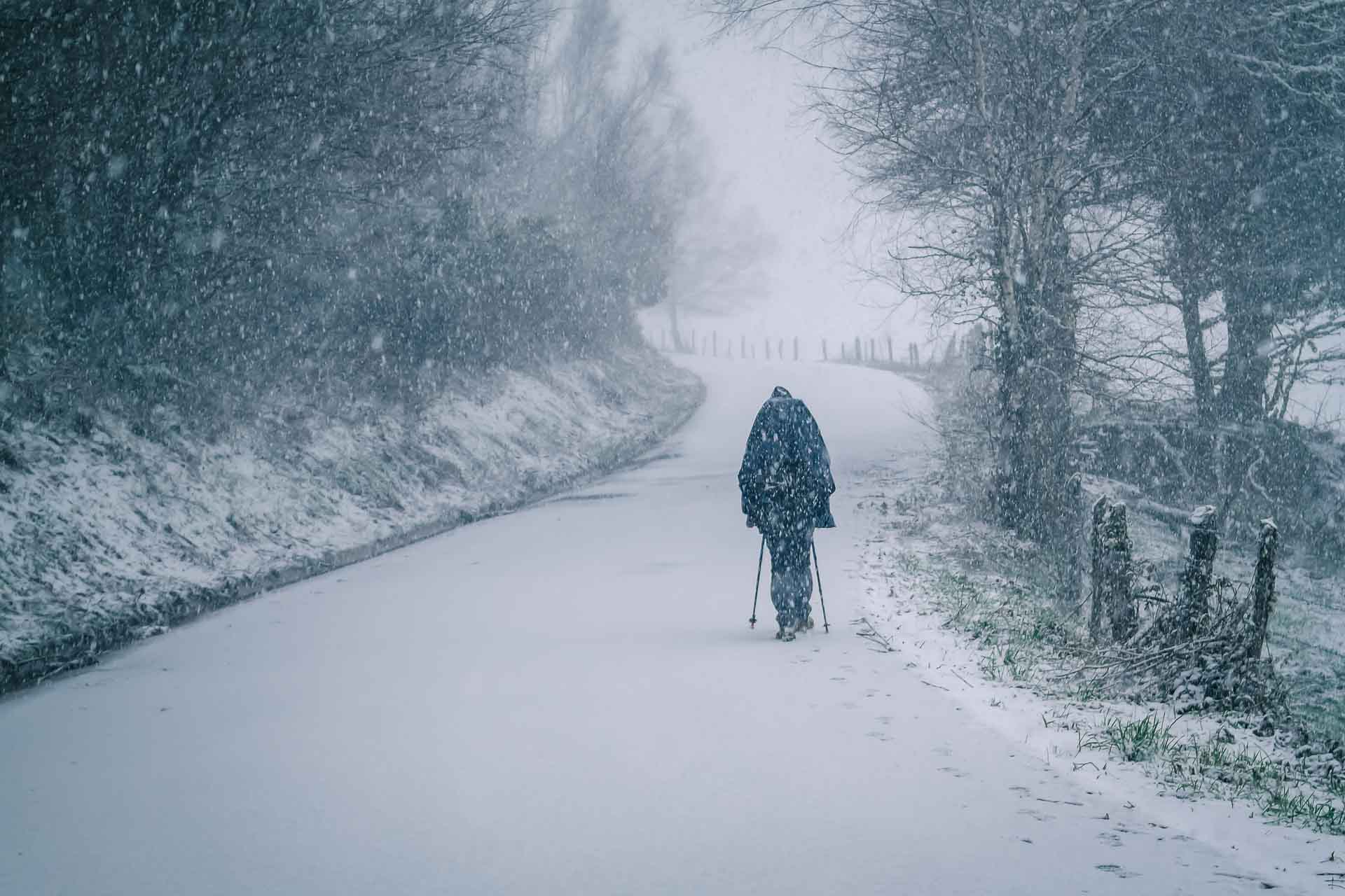 A man walking down a snow covered road.